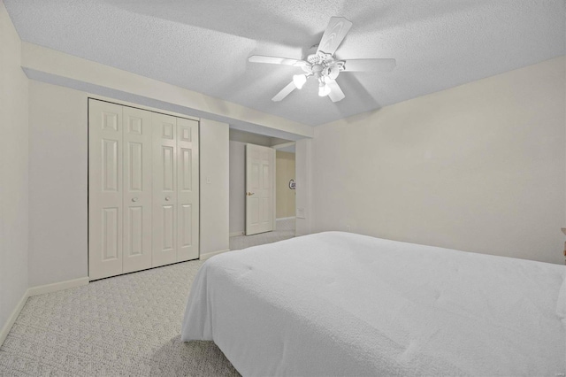 carpeted bedroom with a textured ceiling, a closet, and ceiling fan