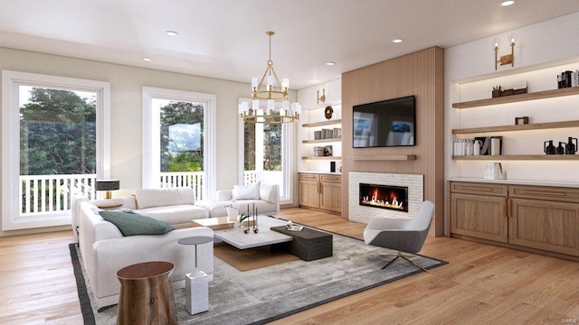 living room featuring a notable chandelier, a fireplace, and light hardwood / wood-style flooring