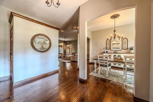 foyer entrance with ceiling fan with notable chandelier and dark hardwood / wood-style floors