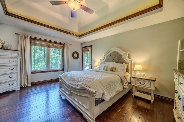 bedroom featuring a raised ceiling, ornamental molding, dark hardwood / wood-style flooring, and ceiling fan