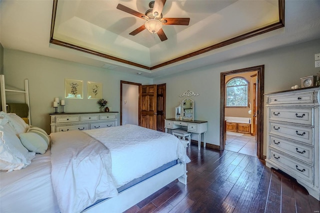 bedroom with ensuite bath, ceiling fan, a raised ceiling, and dark wood-type flooring