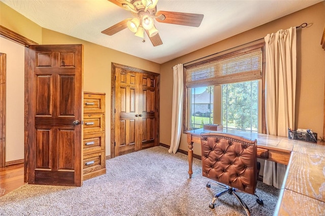 carpeted home office featuring ceiling fan