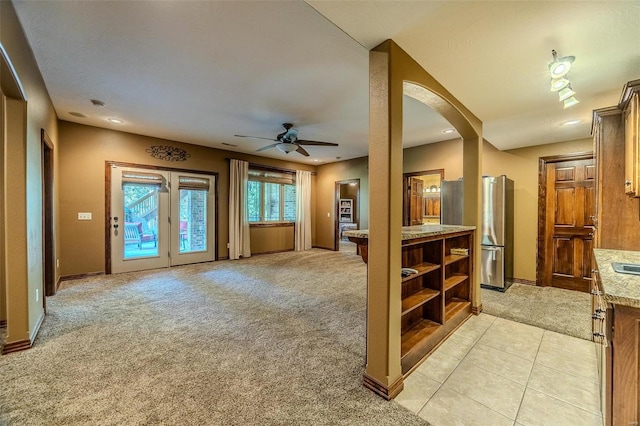 kitchen featuring ceiling fan, stainless steel refrigerator, light stone countertops, and light carpet