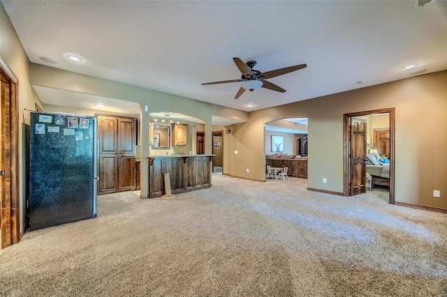 unfurnished living room featuring ceiling fan and light colored carpet