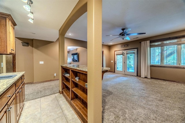 kitchen with light carpet, light stone countertops, and ceiling fan