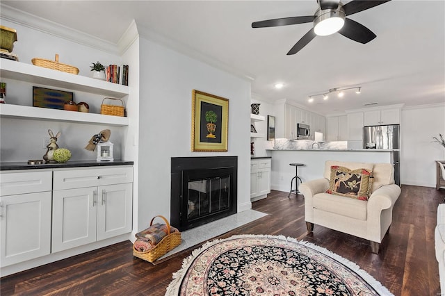 living room with ceiling fan, dark hardwood / wood-style floors, ornamental molding, and built in shelves