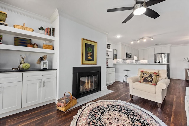 living room featuring ornamental molding, built in shelves, ceiling fan, and dark hardwood / wood-style flooring