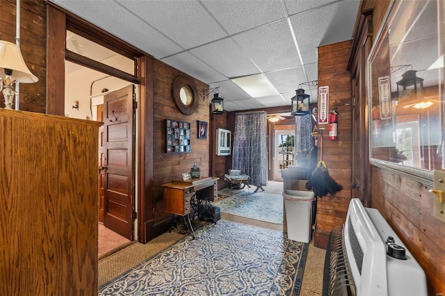 office with a drop ceiling, wood walls, and carpet flooring