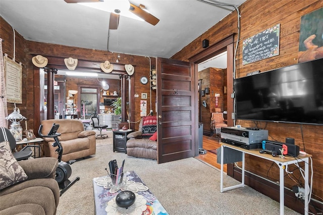 carpeted living room featuring ceiling fan and wooden walls