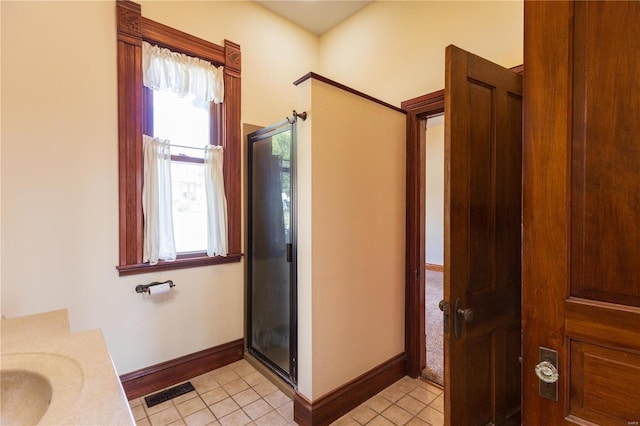 bathroom featuring vanity, a shower with shower door, and tile patterned floors