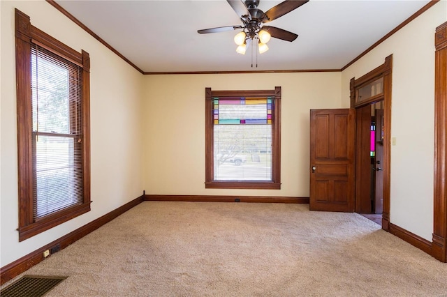 carpeted spare room featuring crown molding and ceiling fan