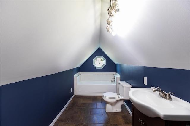 bathroom featuring vanity, a tub to relax in, toilet, and lofted ceiling