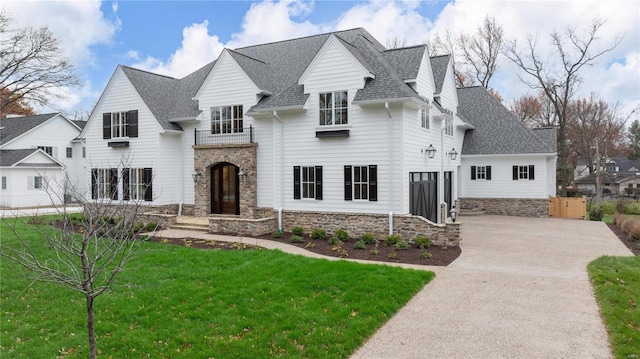 view of front of house with a shingled roof, concrete driveway, and a front lawn