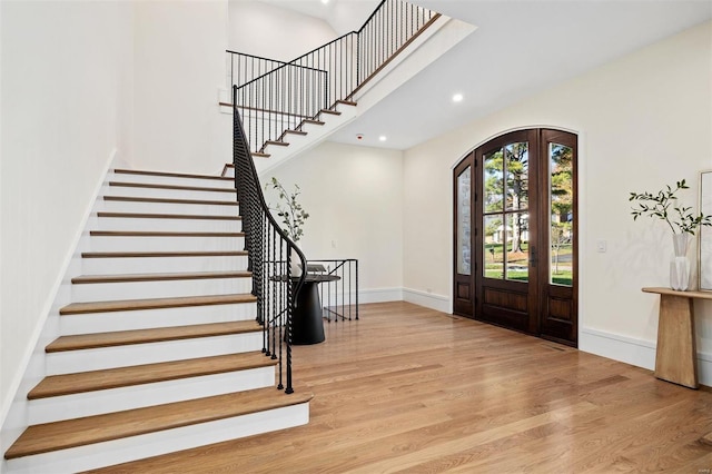 foyer entrance featuring arched walkways, baseboards, and wood finished floors