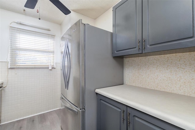 kitchen with ceiling fan, stainless steel fridge, hardwood / wood-style floors, and gray cabinetry