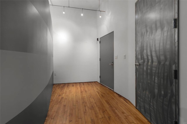 corridor with light hardwood / wood-style flooring and track lighting