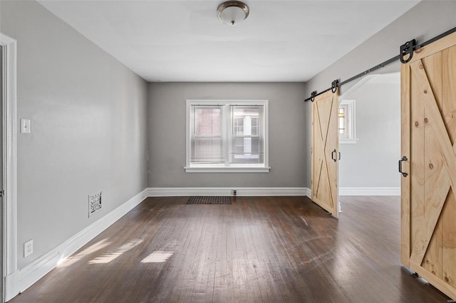 spare room featuring dark wood-type flooring and a barn door