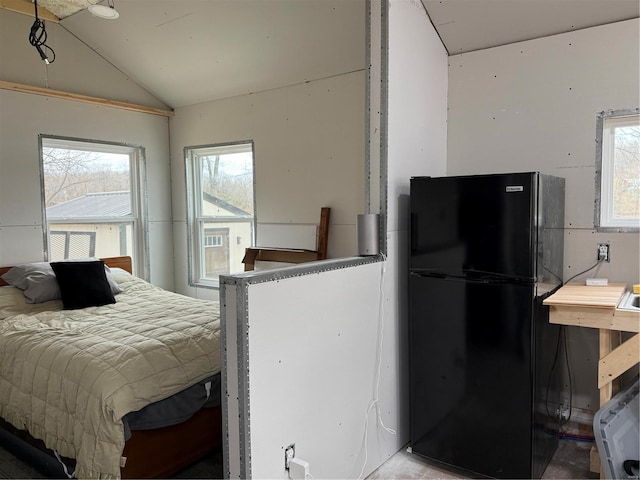 interior space featuring vaulted ceiling, black fridge, and multiple windows