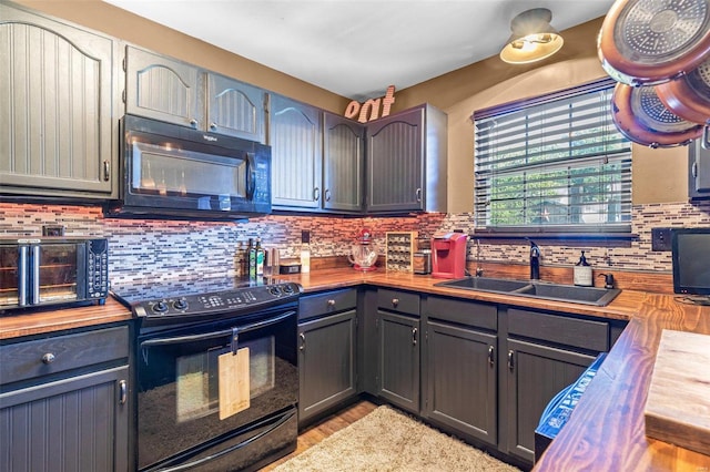 kitchen with gray cabinets, wooden counters, black appliances, and sink