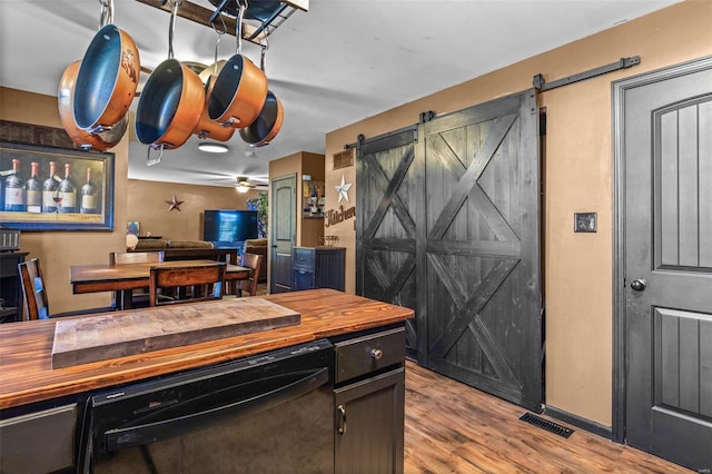 kitchen with dishwasher, a barn door, light hardwood / wood-style flooring, and ceiling fan