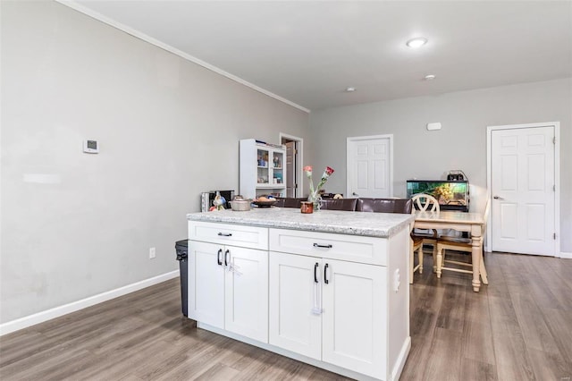 kitchen featuring light stone countertops, light hardwood / wood-style floors, white cabinetry, and ornamental molding