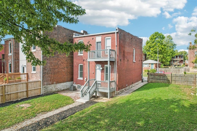 rear view of house with a balcony and a lawn