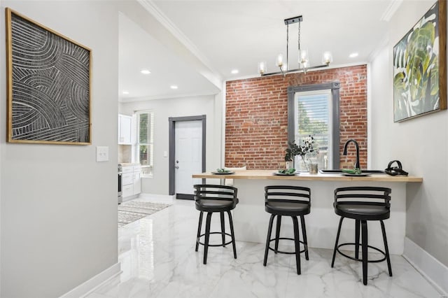 kitchen featuring crown molding, a notable chandelier, a breakfast bar, and brick wall