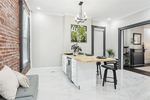 kitchen featuring wooden counters, white cabinetry, a breakfast bar area, a chandelier, and decorative light fixtures