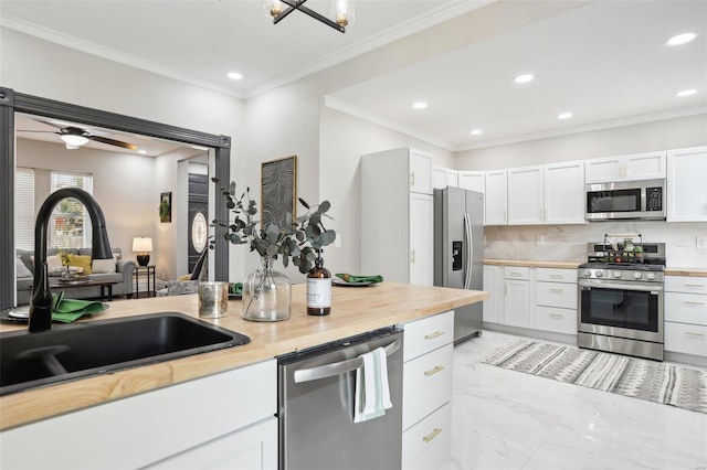 kitchen featuring white cabinets, appliances with stainless steel finishes, crown molding, and sink