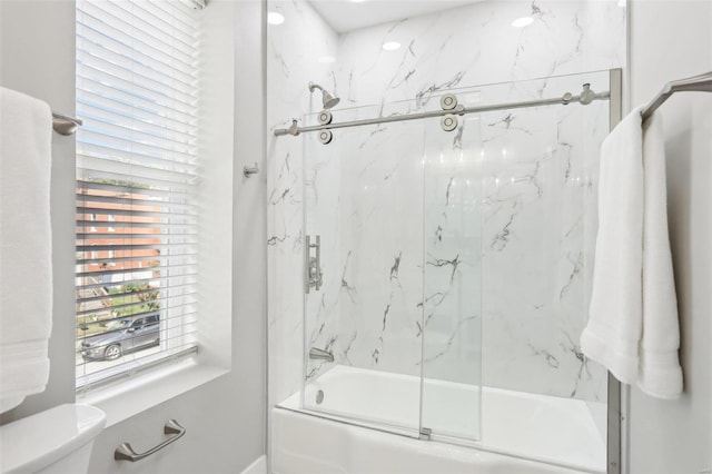 bathroom featuring toilet and shower / bath combination with glass door