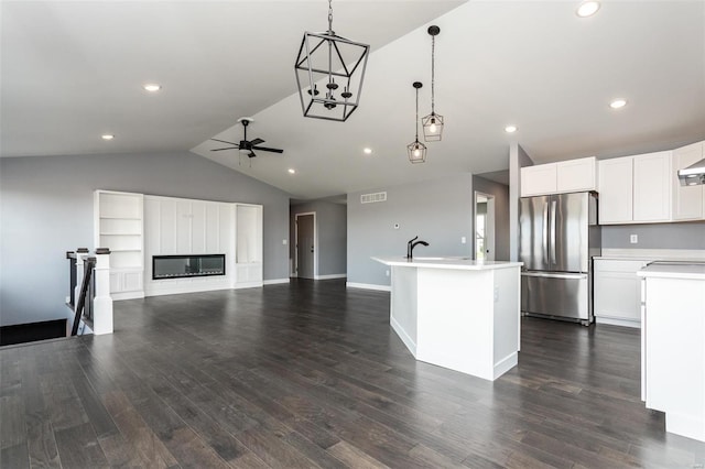 kitchen with stainless steel fridge, dark hardwood / wood-style flooring, a kitchen island with sink, and vaulted ceiling