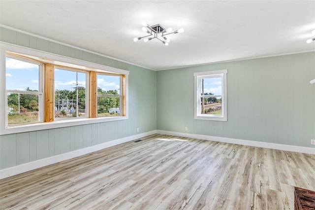 unfurnished room with light hardwood / wood-style flooring, a chandelier, and crown molding