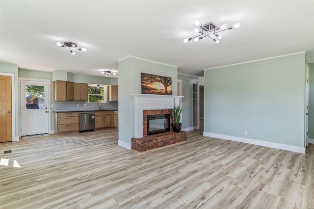 unfurnished living room featuring a notable chandelier, light hardwood / wood-style floors, ornamental molding, and a brick fireplace