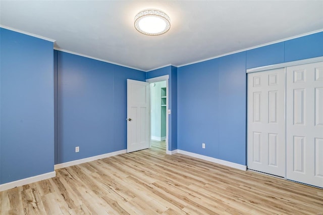 unfurnished bedroom featuring ornamental molding, light hardwood / wood-style flooring, and a closet