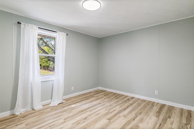 spare room featuring crown molding and light hardwood / wood-style floors