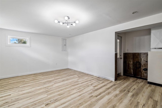 spare room with light wood-type flooring, electric panel, and a notable chandelier