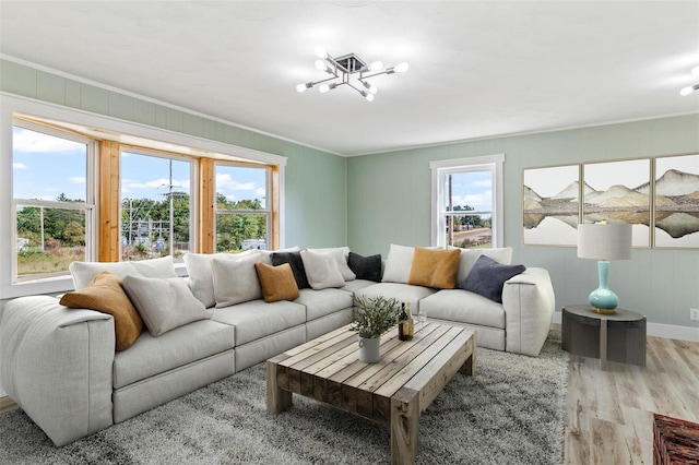 living room featuring light hardwood / wood-style flooring, a chandelier, and crown molding