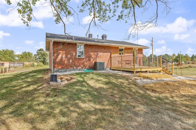 rear view of house with a yard, brick siding, cooling unit, and a wooden deck