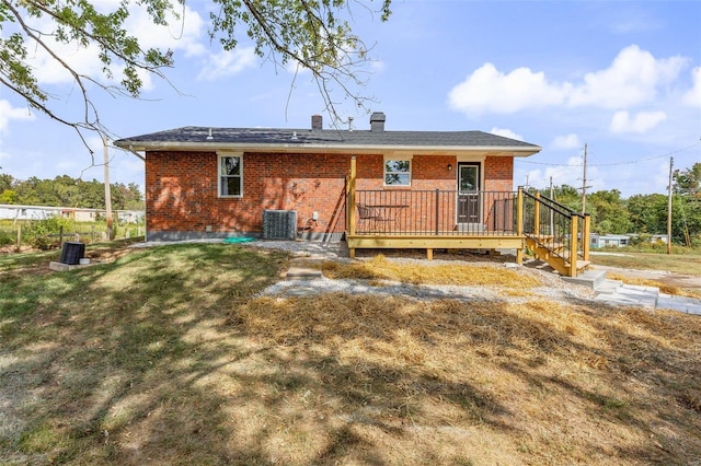 back of house with brick siding, a chimney, a lawn, cooling unit, and a wooden deck