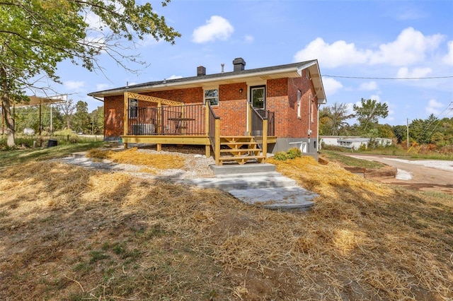 rear view of property featuring a wooden deck, a chimney, and brick siding