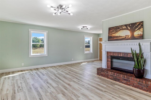 unfurnished living room featuring plenty of natural light, a fireplace, light wood-style flooring, and baseboards