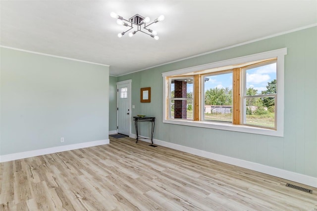 empty room with light wood finished floors, baseboards, visible vents, ornamental molding, and a notable chandelier