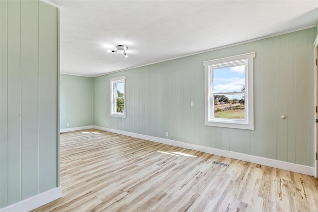 empty room with light wood finished floors, baseboards, and visible vents