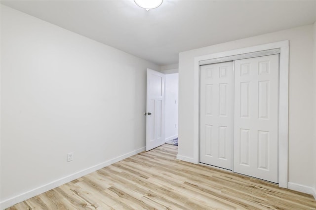 unfurnished bedroom featuring light wood finished floors, a closet, and baseboards