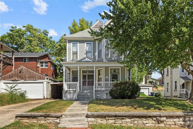 view of front of home with a porch, an outbuilding, a front yard, and a garage