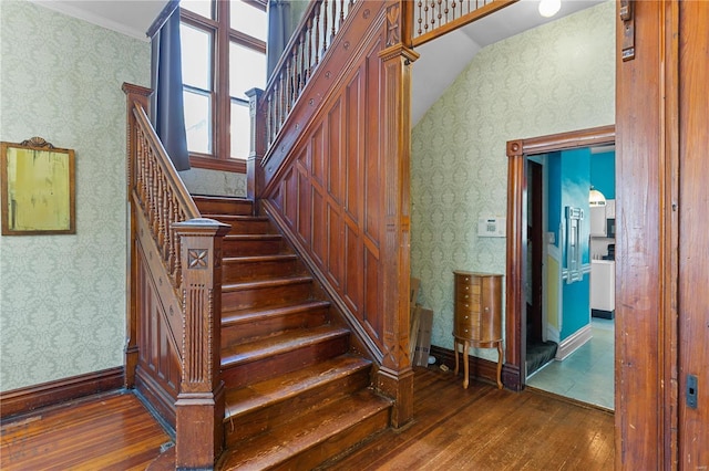 stairs featuring wood-type flooring, ornamental molding, and vaulted ceiling