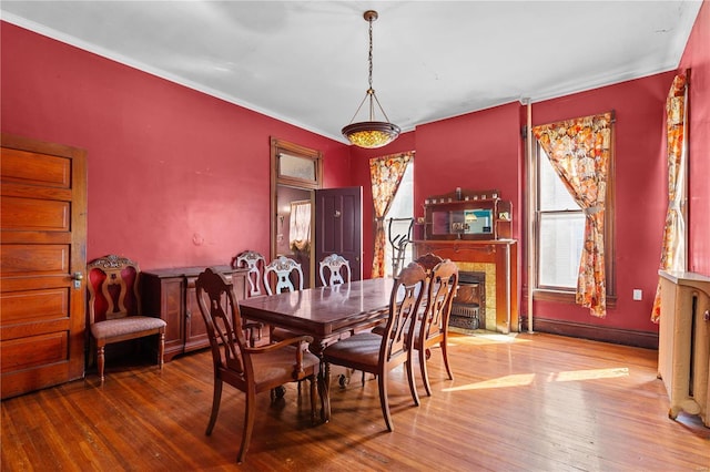 dining space featuring a high end fireplace, wood-type flooring, and ornamental molding