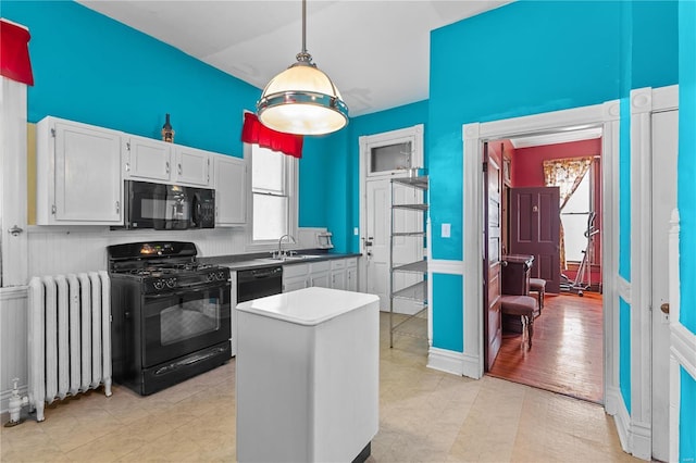 kitchen with radiator, white cabinetry, light hardwood / wood-style flooring, pendant lighting, and black appliances