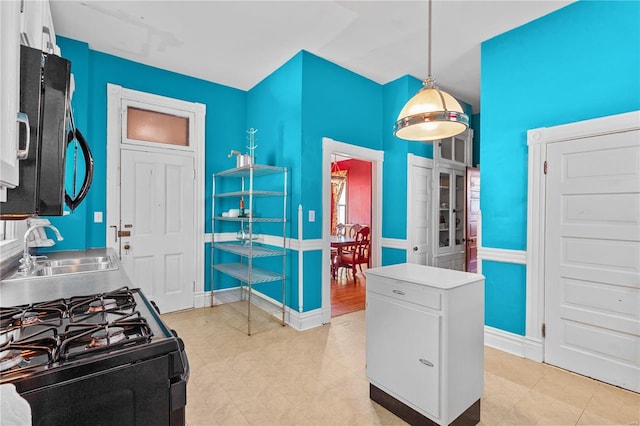 kitchen featuring black gas range, decorative light fixtures, white cabinetry, and sink