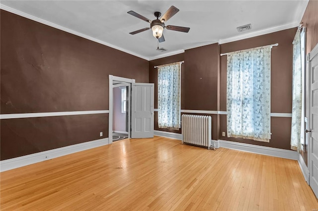 unfurnished room featuring ceiling fan, light wood-type flooring, radiator heating unit, and ornamental molding